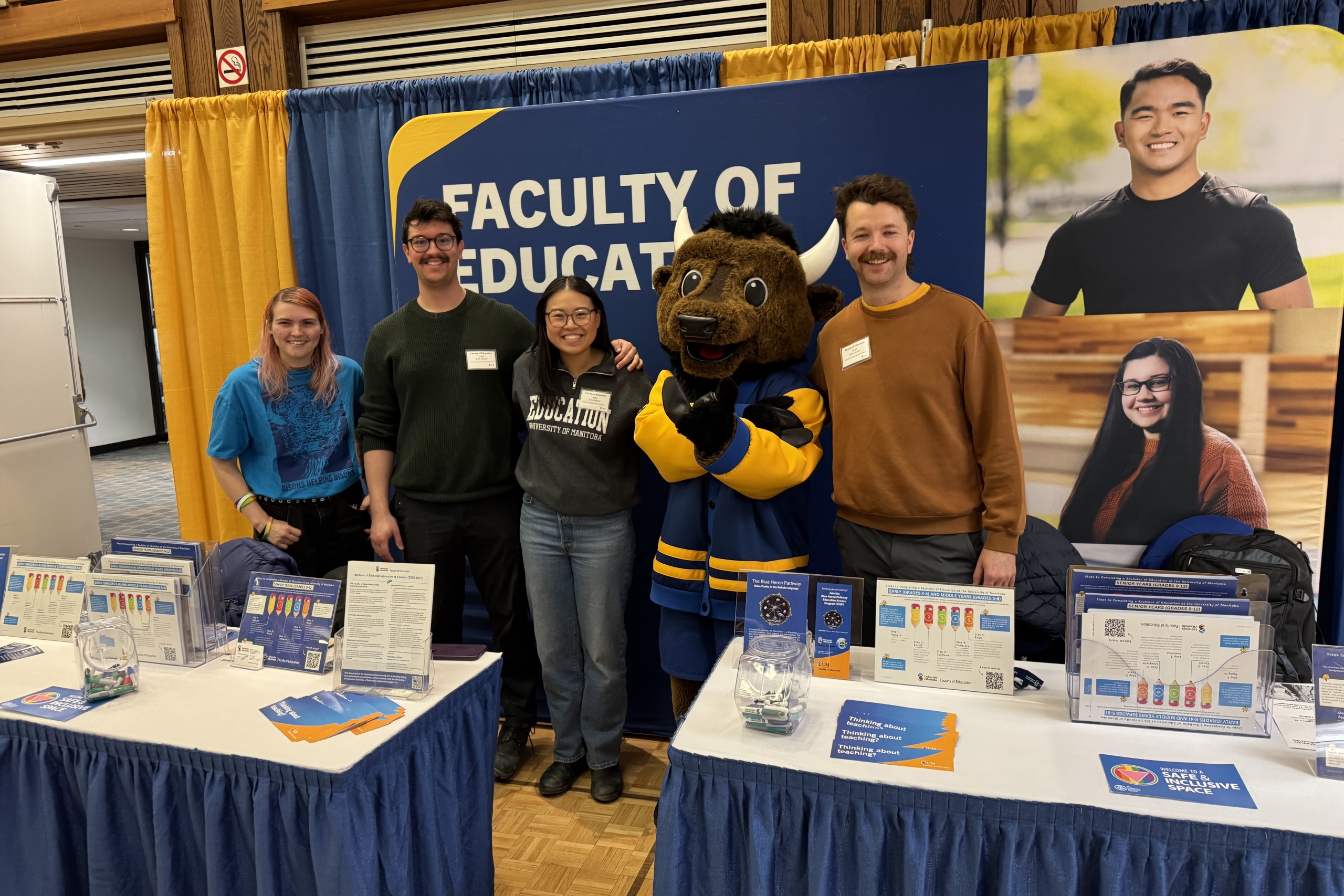 students standing at career fair table with bison mascot