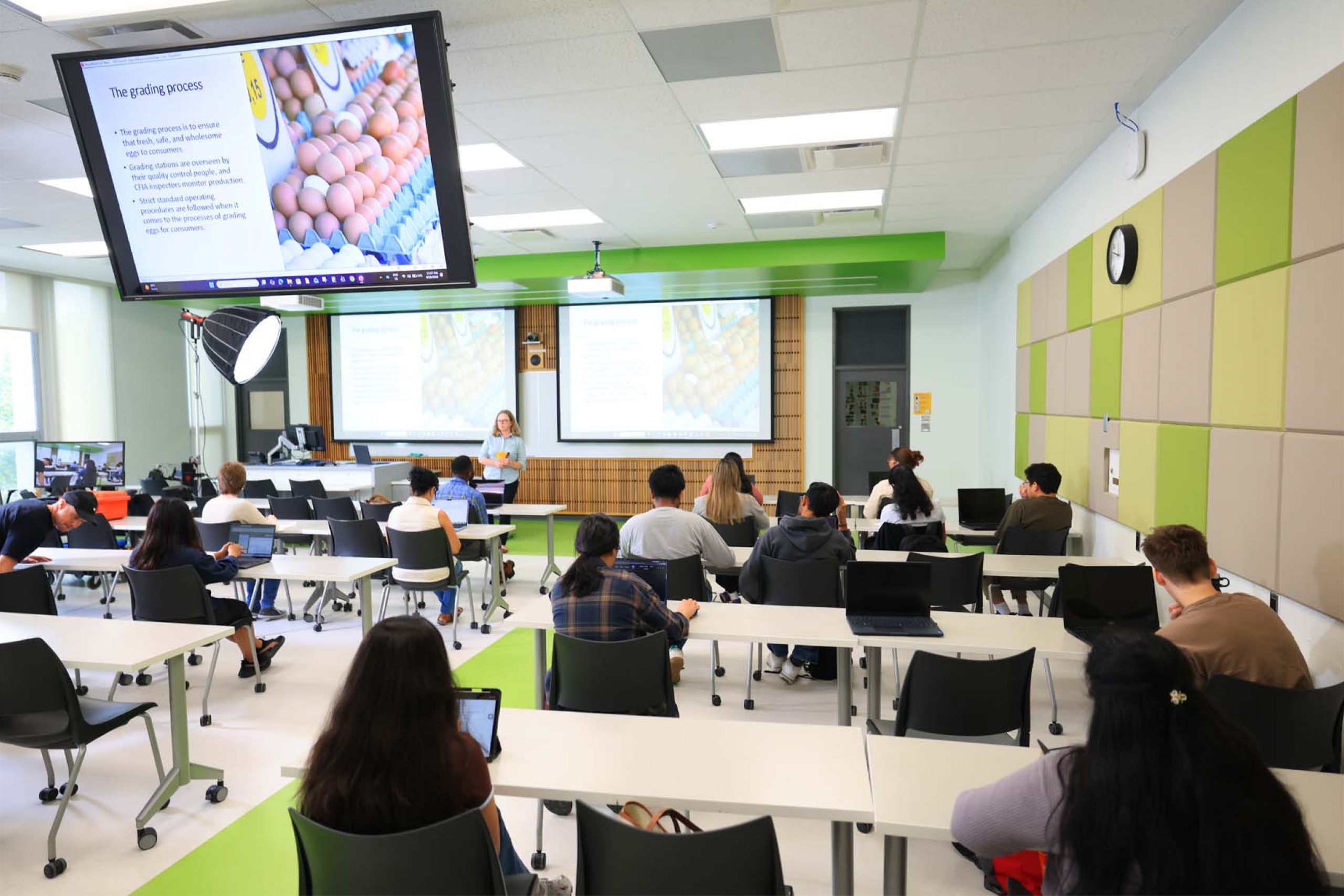 Rows of students learn in a modern, bright classroom.