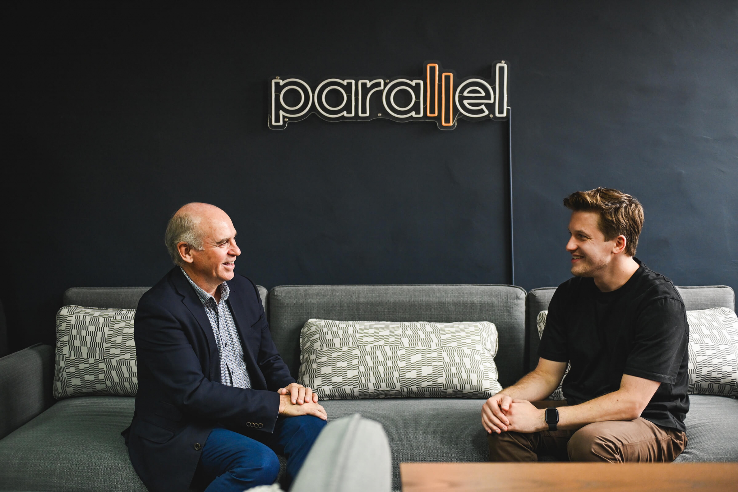 Chancellor Dave Angus sits on a sofa facing entrepreneur and alum Chris Schmidt