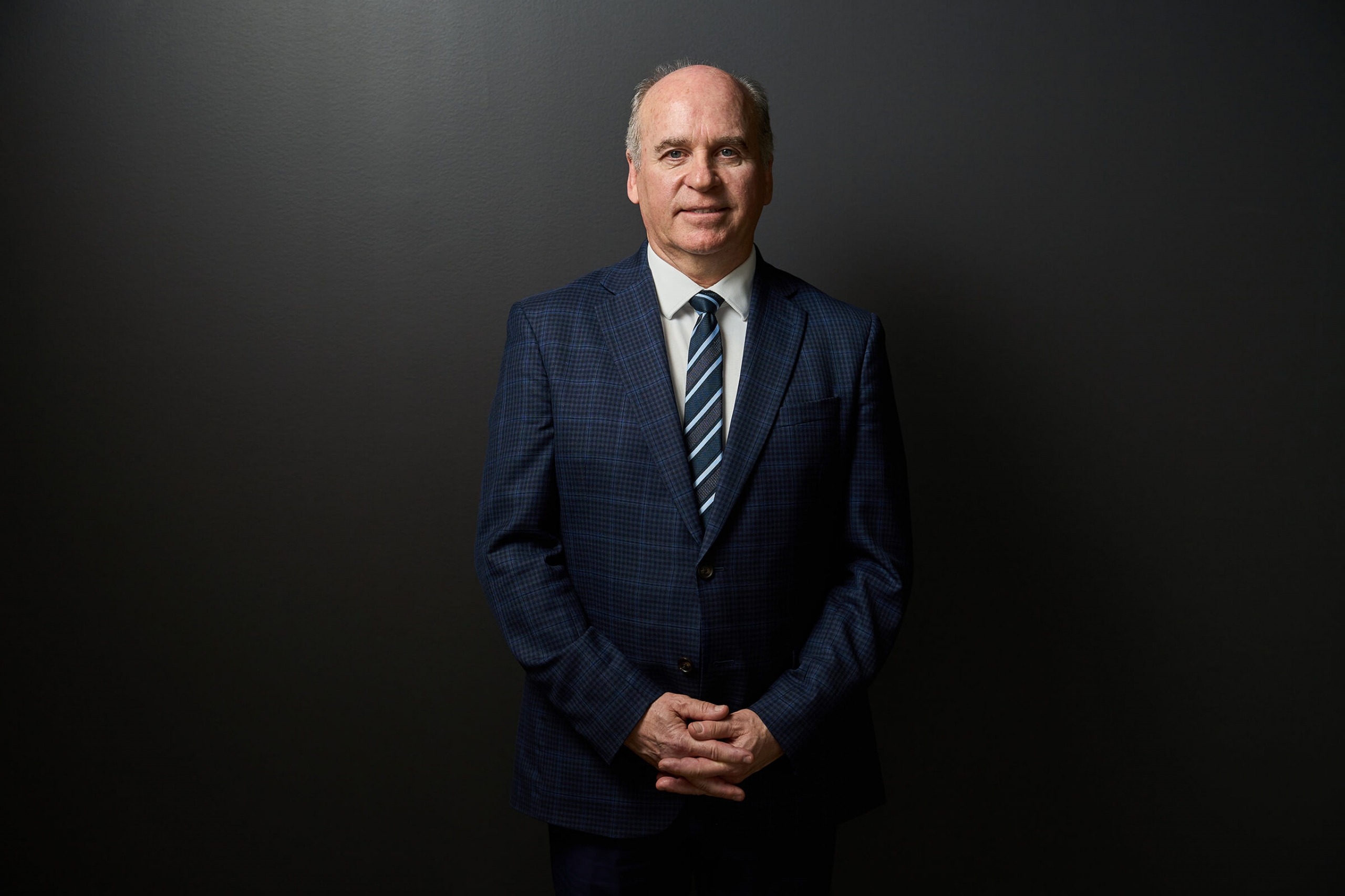 A man in a blue suit (Dave Angus) smiles for the camera
