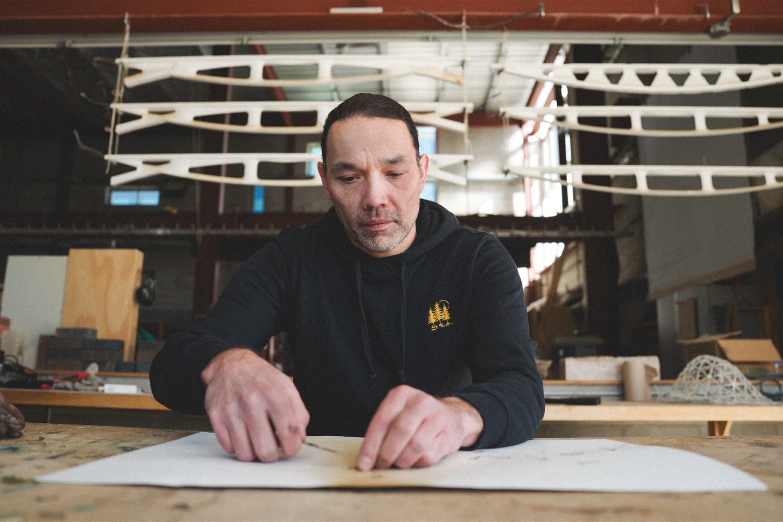 A man (Ryan Gorrie) sits at a desk working on his art