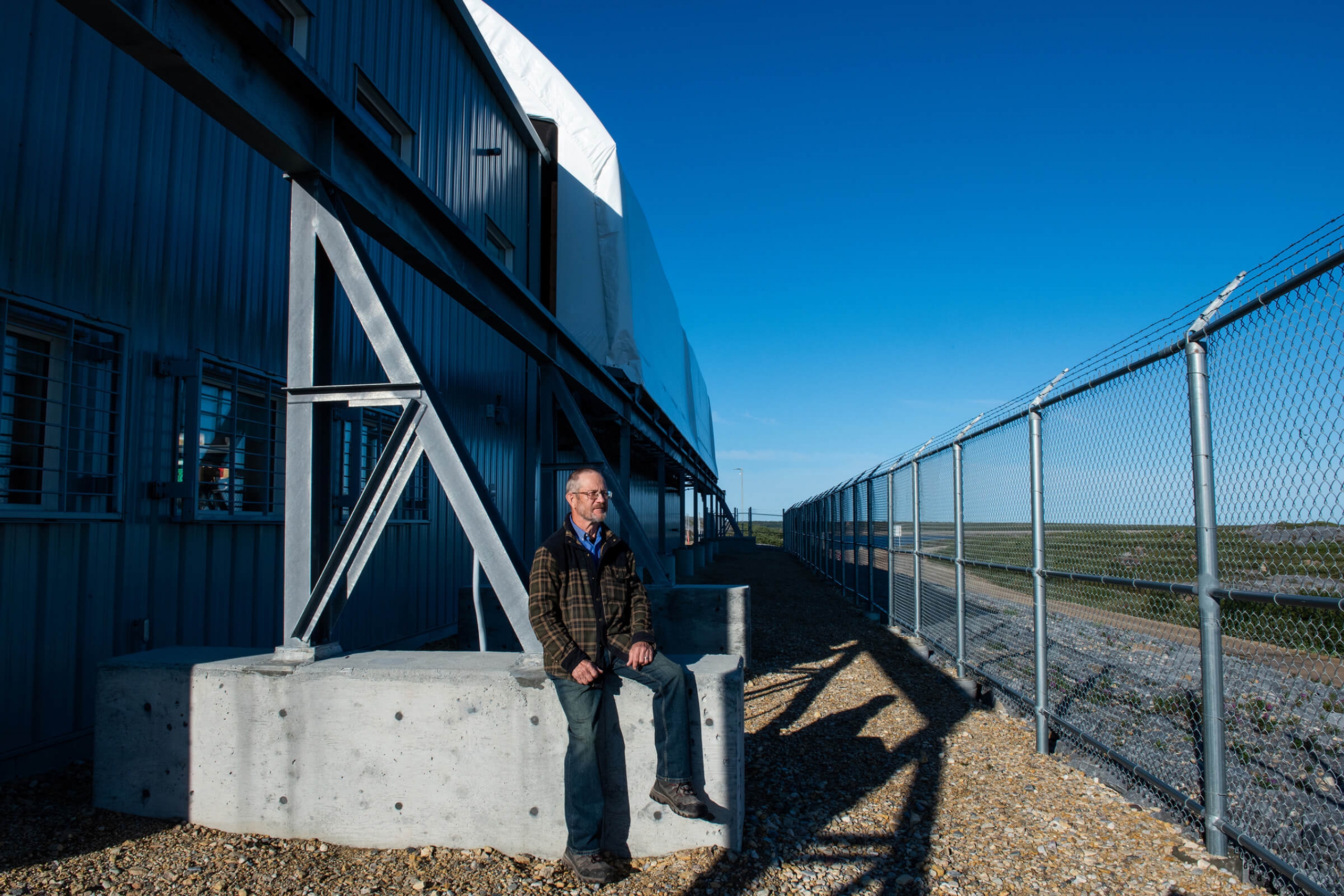 A man leans against a concrete block outside a research facility