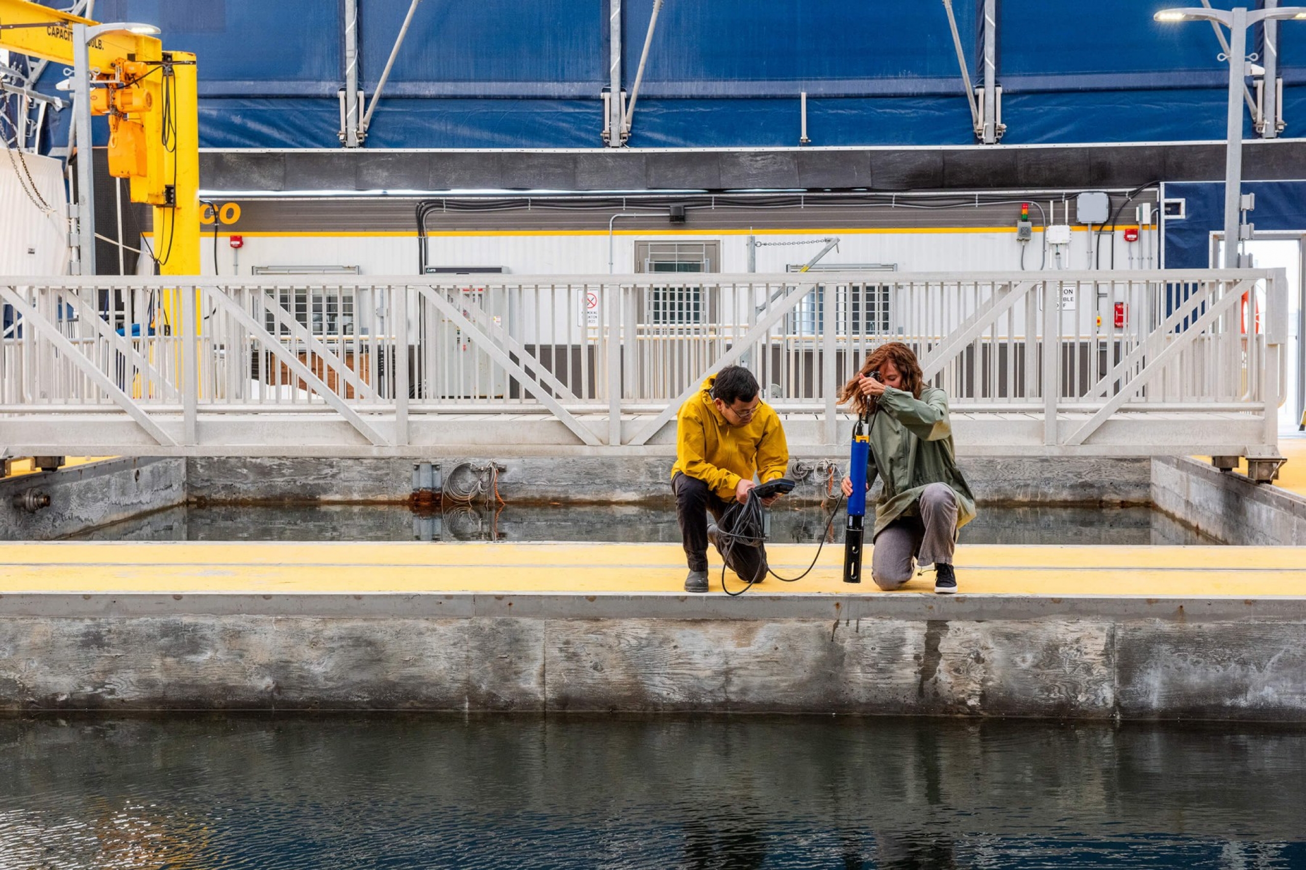 Two researchers sampling water from a pool