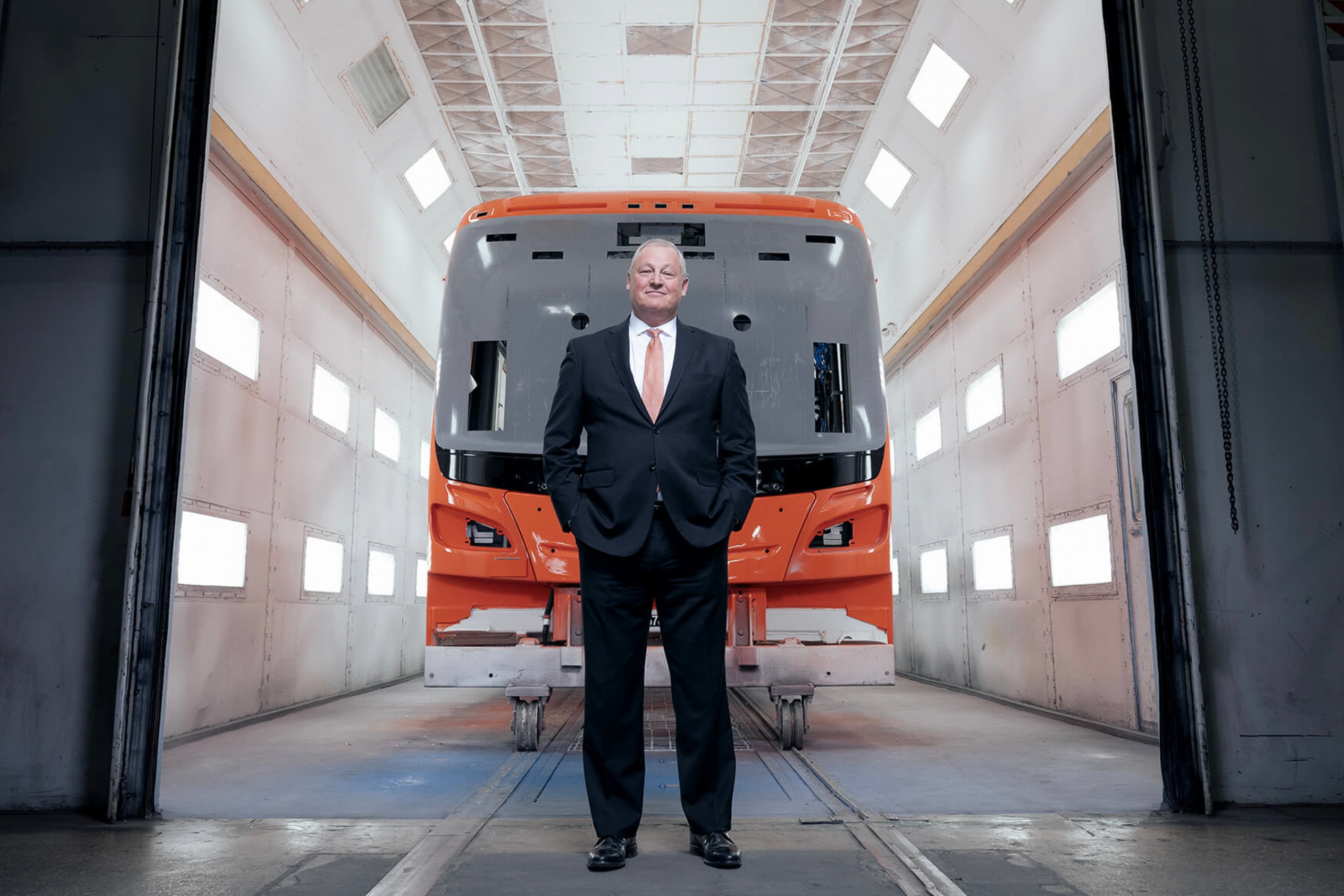 Paul Soubry faces the camera, stood in front of a bus in a warehouse tunnel