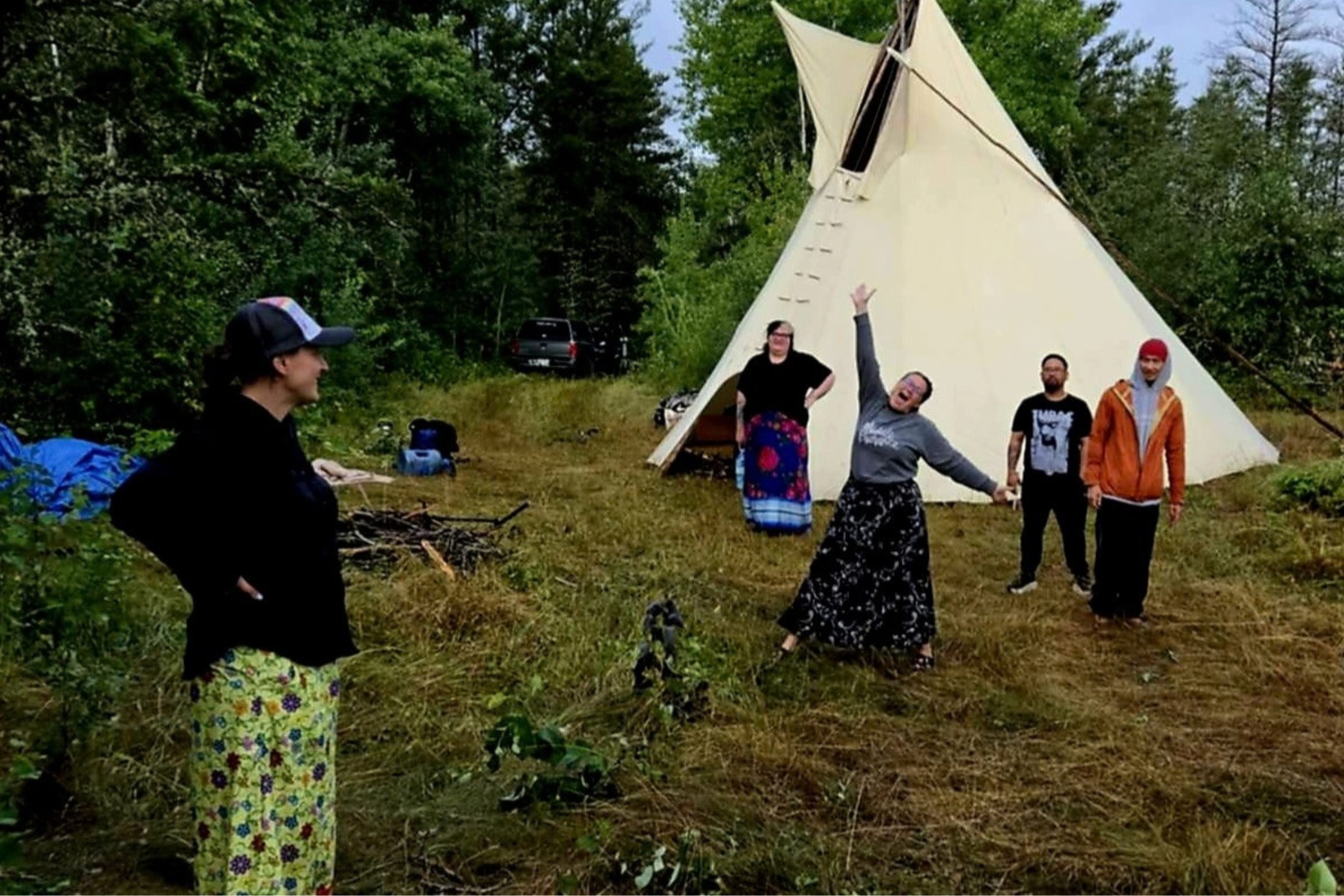 students standing outdoors with tipi
