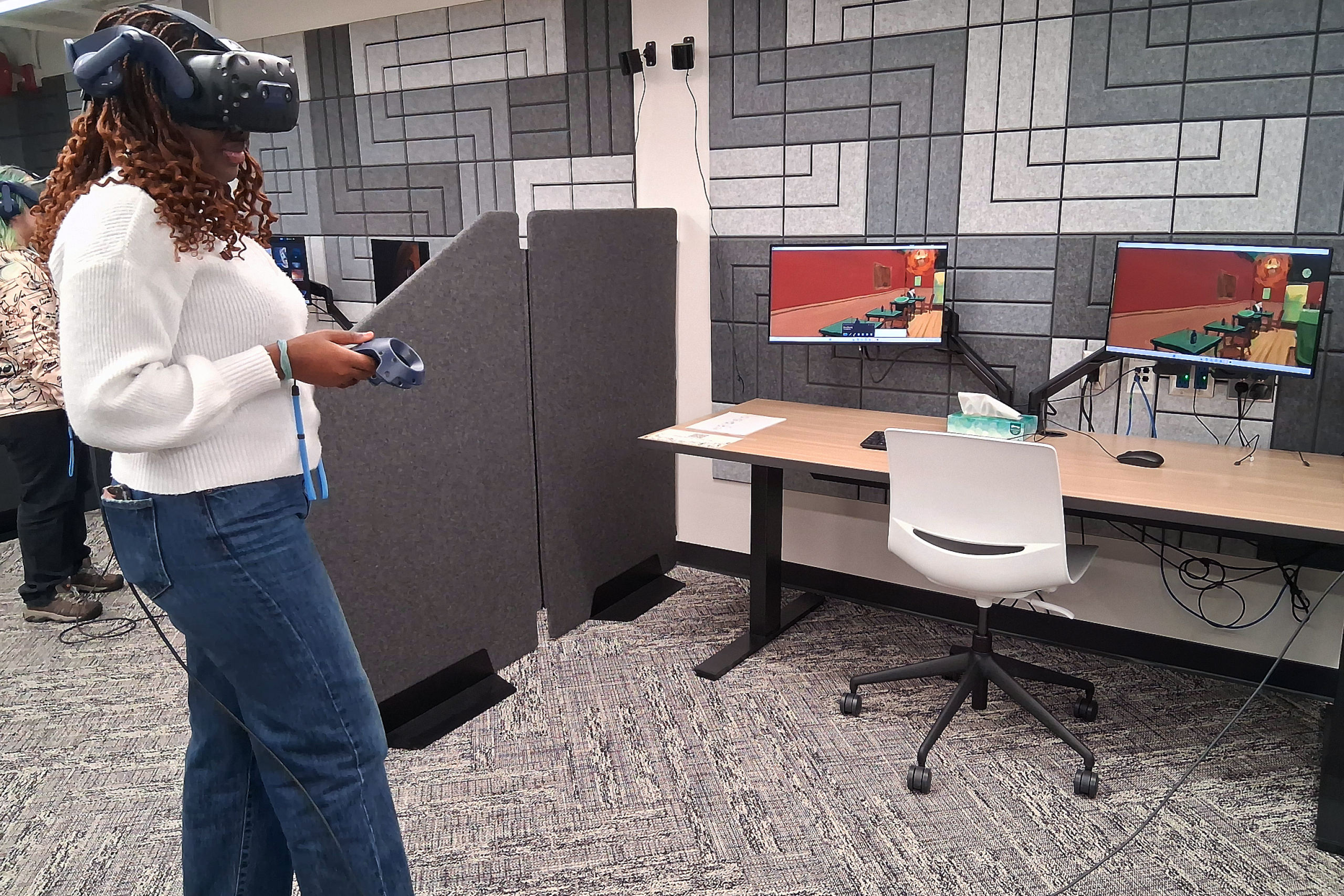 A woman using a VR headset in front of computers